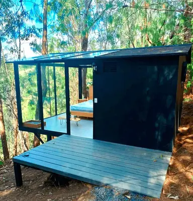 Cabaña de vidrio CONCASAYA con estructura de vidrio panorámica y deck de madera, ideal para glamping premium